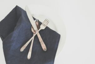 gray fork, spoon, and butter knife on plate with black table napkin